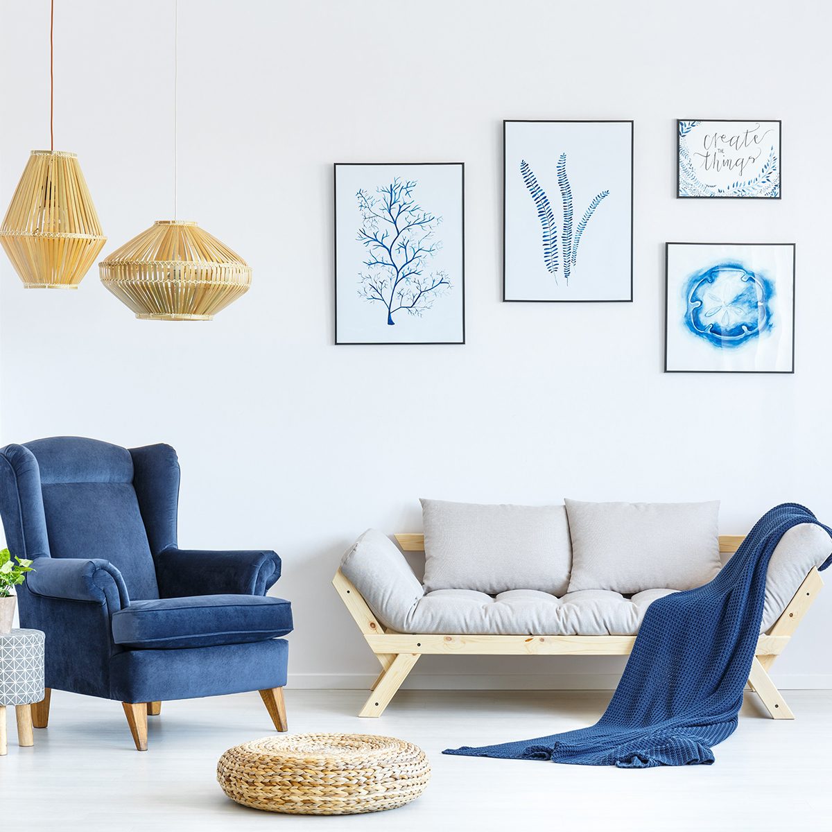 White and blue living room with sofa, armchair, lamp, posters