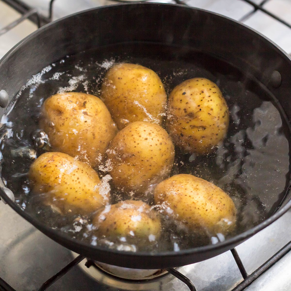 Potatoes boiling in a saucepan on a gas hob.