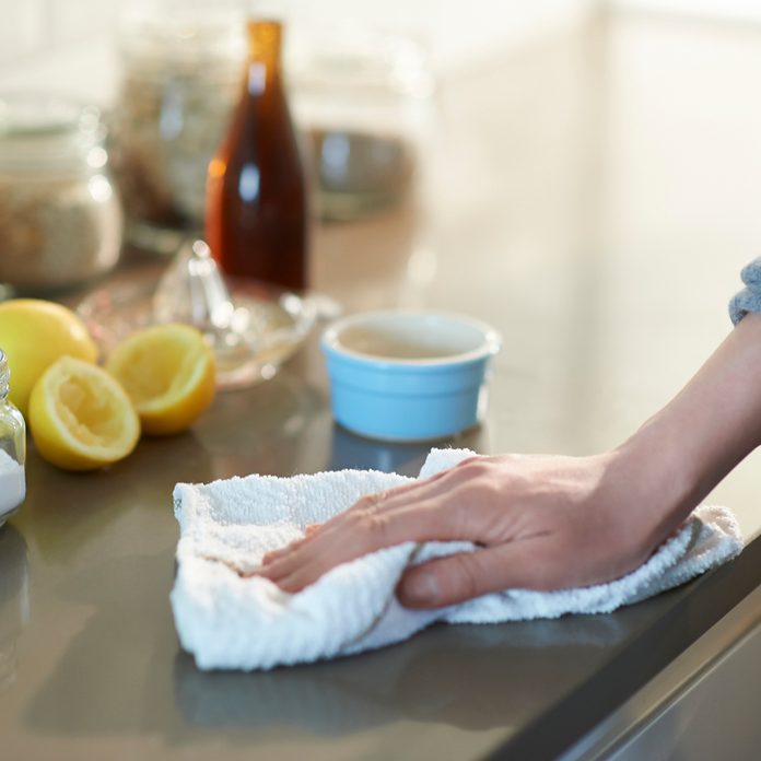 Woman cleaning a kitchen worktop with natural cleaning products lemon, bicarbonate of soda and vinegar.