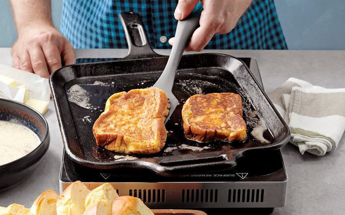 how to make french toast The Best French Toast; How to Step 6; flip to other side; cook to golden brown; half-and-half cream; egg yolks; brown sugar; vanilla extract; ground cinnamon; ground nutmeg; brioche bread; butter; maple syrup; fresh berries; whipped cream; confectioners' sugar; powder sugar; hands