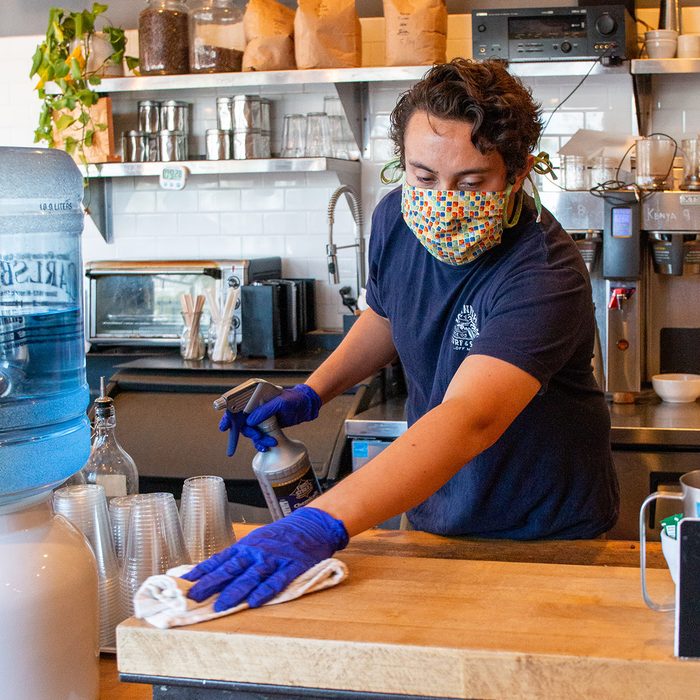Man working in a coffee shop wearing a mask