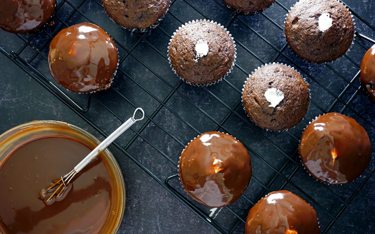 dipping filled chocolate copycat Hostess cupcakes into ganache