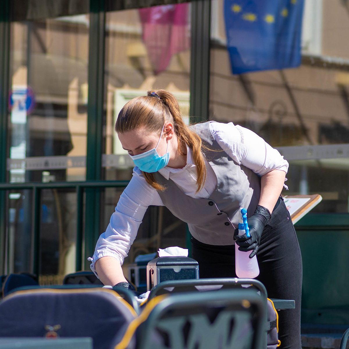Waitress with a mask disinfects the table