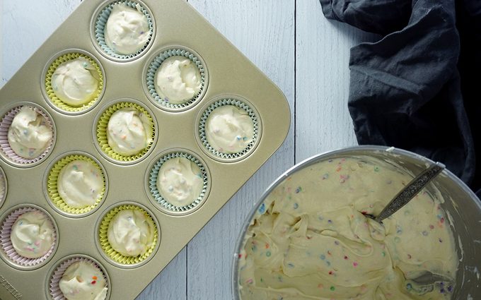 filling cupcake liners with birthday cupcake batter