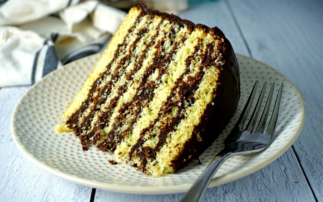 a close-up photo of a slice of smith island cake on a plate with a fork