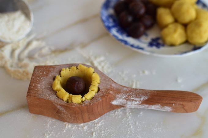 Date ball inserted into hollowed dough in the mold for ma'amoul cookies