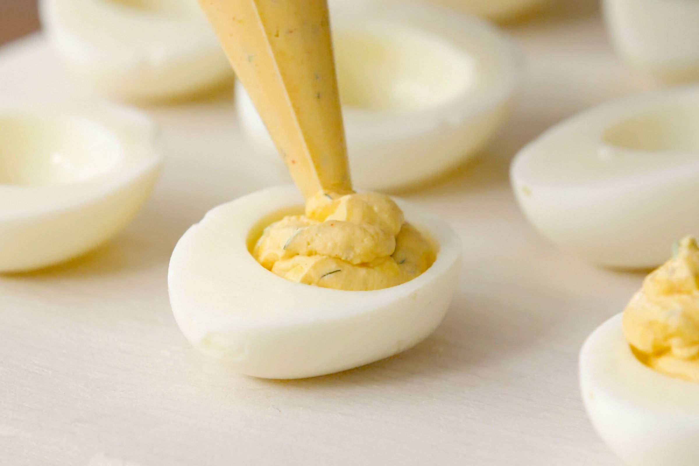 filling half of a hard boiled egg with deviled egg mixture