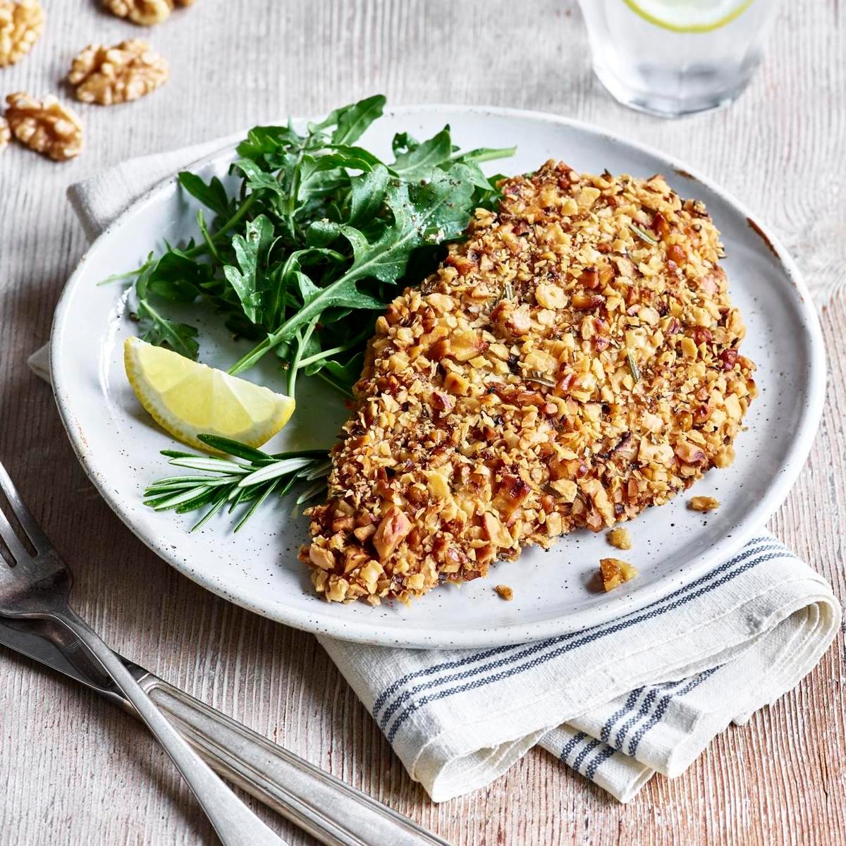 A piece of herbed matzo and walnut-crusted chicken on a plate.