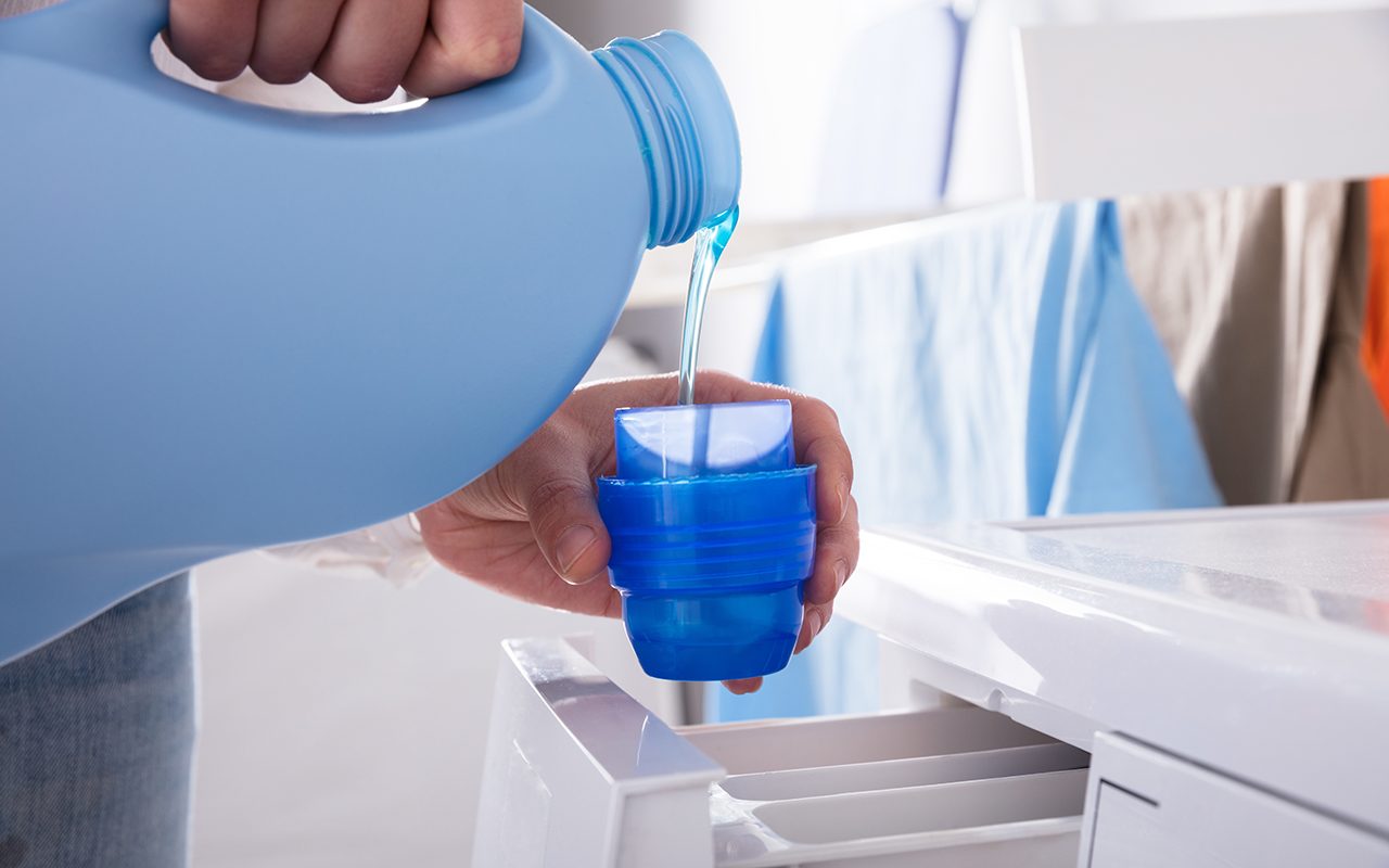 Person Pouring Detergent In Lid