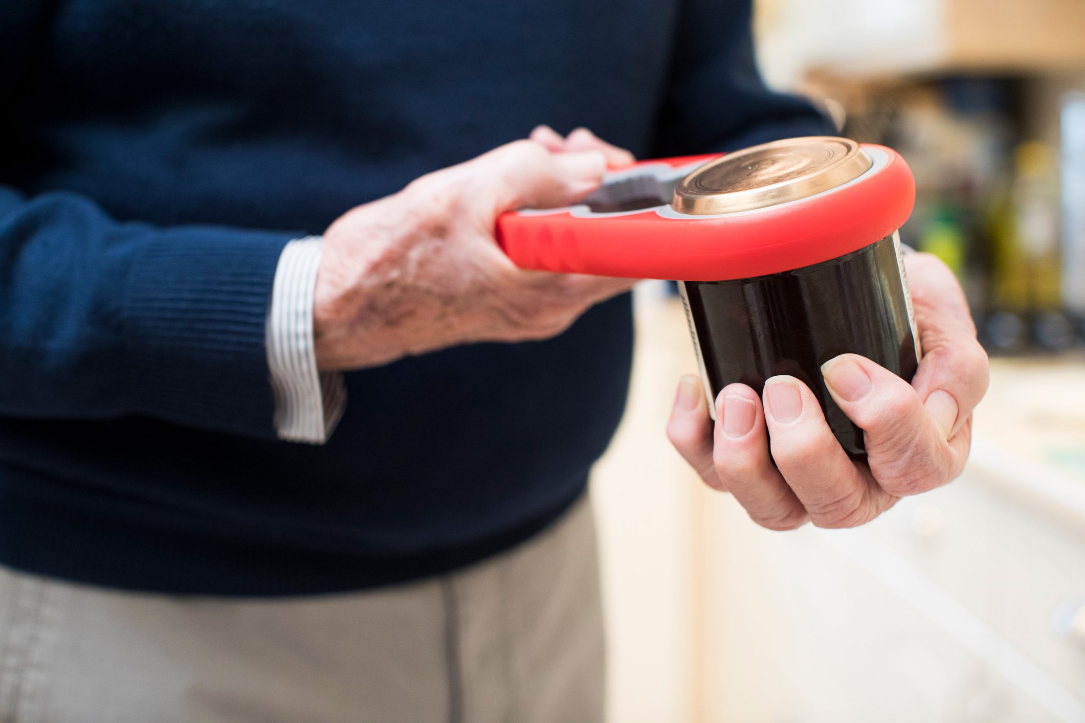 Close Up Of Senior Man Taking Lid Off Jar With jar opening tool