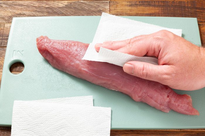 A Person Cleaning Meat on a Cutting Board