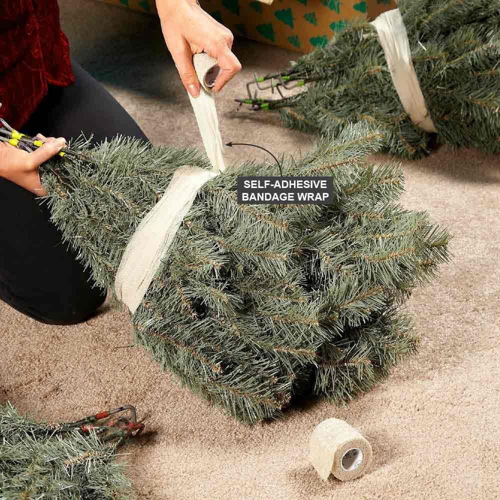 person using soft bandage wrapping to wrap pieces of an artificial christmas tree for storage