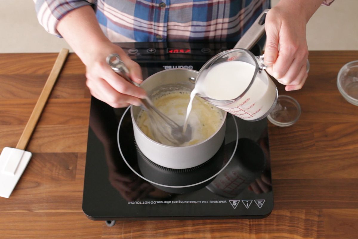 person pouring milk into gravy mixture