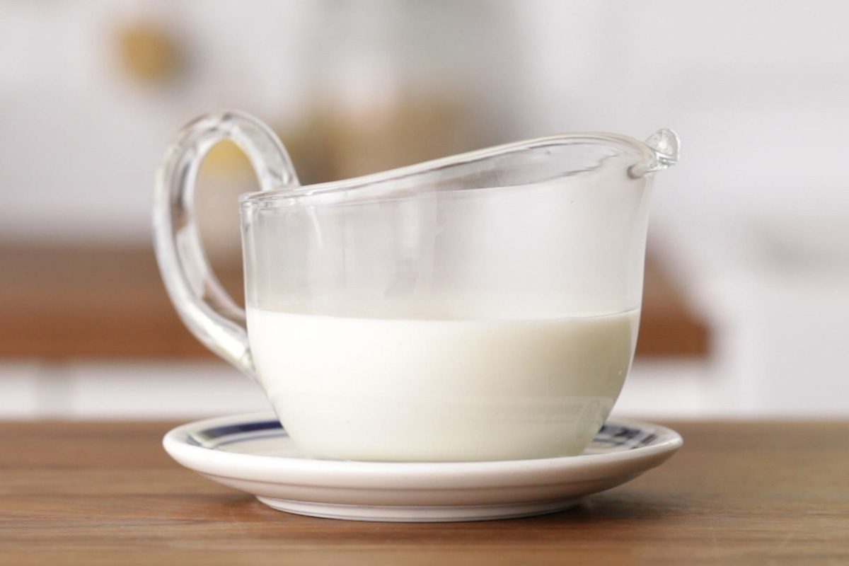 glass gravy boat with white gravy on wood table