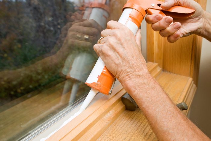 Hands Applying Weather Seal Caulk to Window Frame