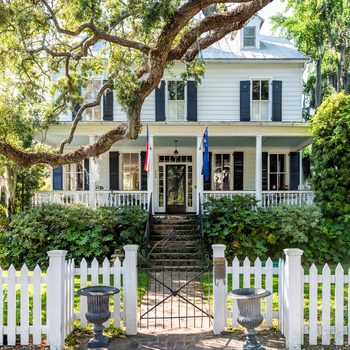 Typical American residential house building in Charleston, South Carolina area with American flag and white picket fence