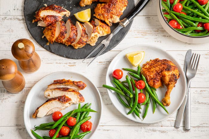 Air Fryer Whole Chicken Served in Stone and Ceramic Plates on Wooden Surface with Fork and Knife