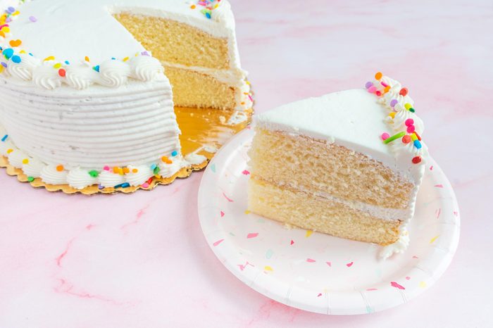 safeway grocery store cake with a slice from it sitting next to the cake on pink background