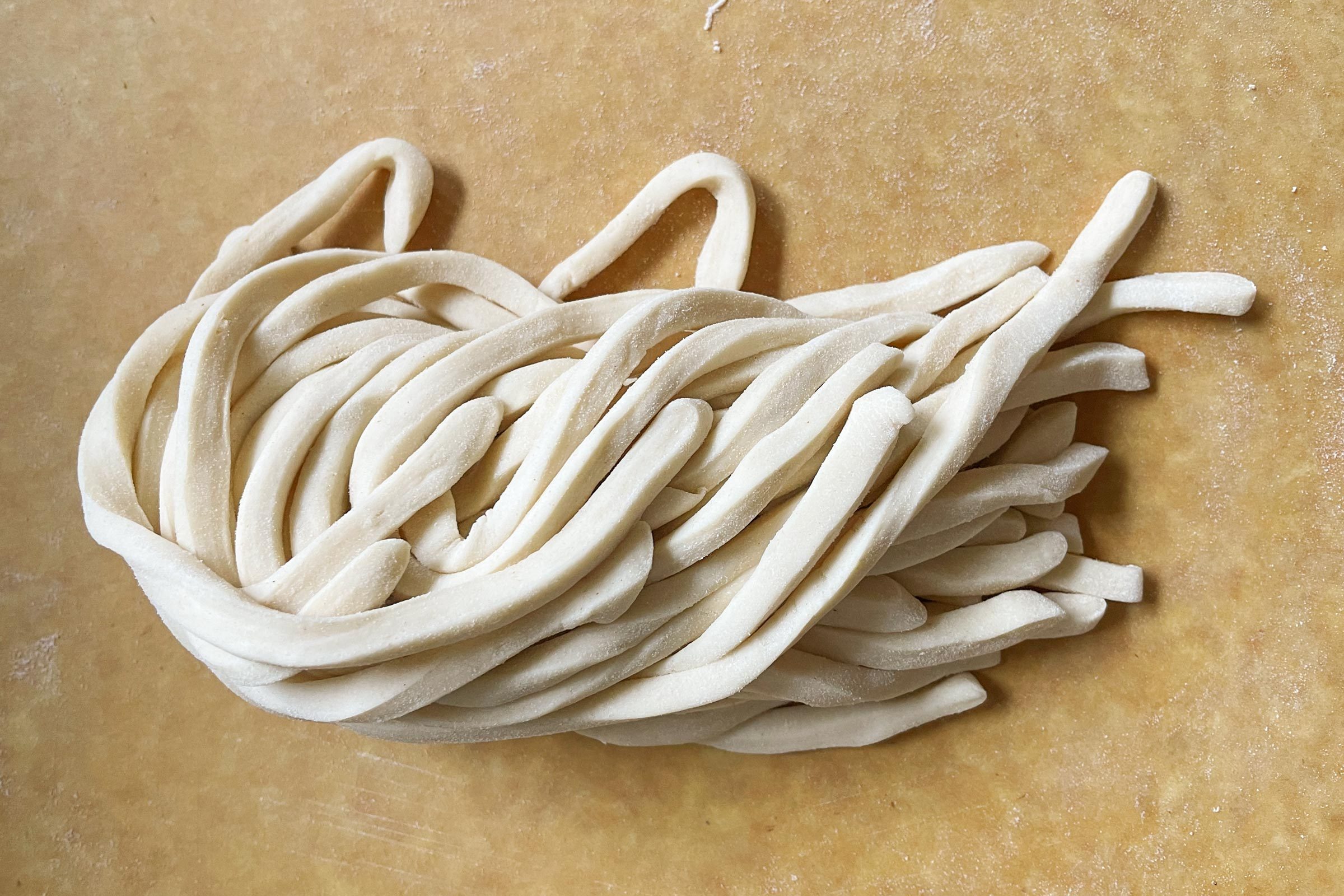 raw udon noodles on cutting board