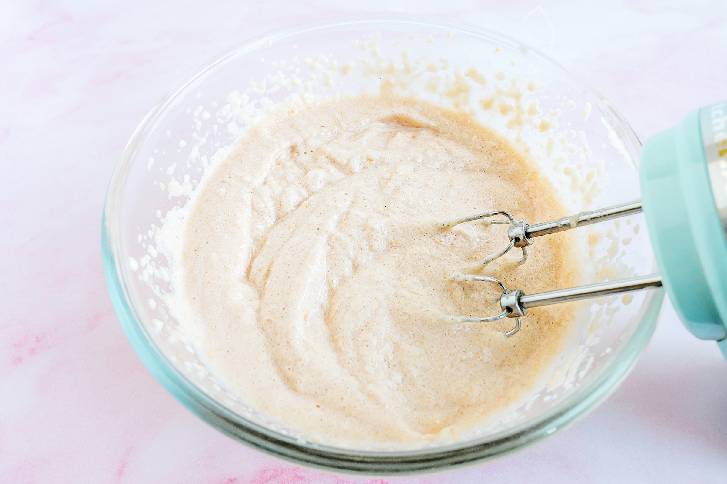 mixing ingredients for strawberry cloud cake with an electric mixer