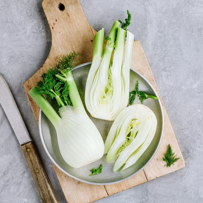 Fresh raw organic florence fennel bulbs or fennel bulb on wooden cutting board on gray stone surface