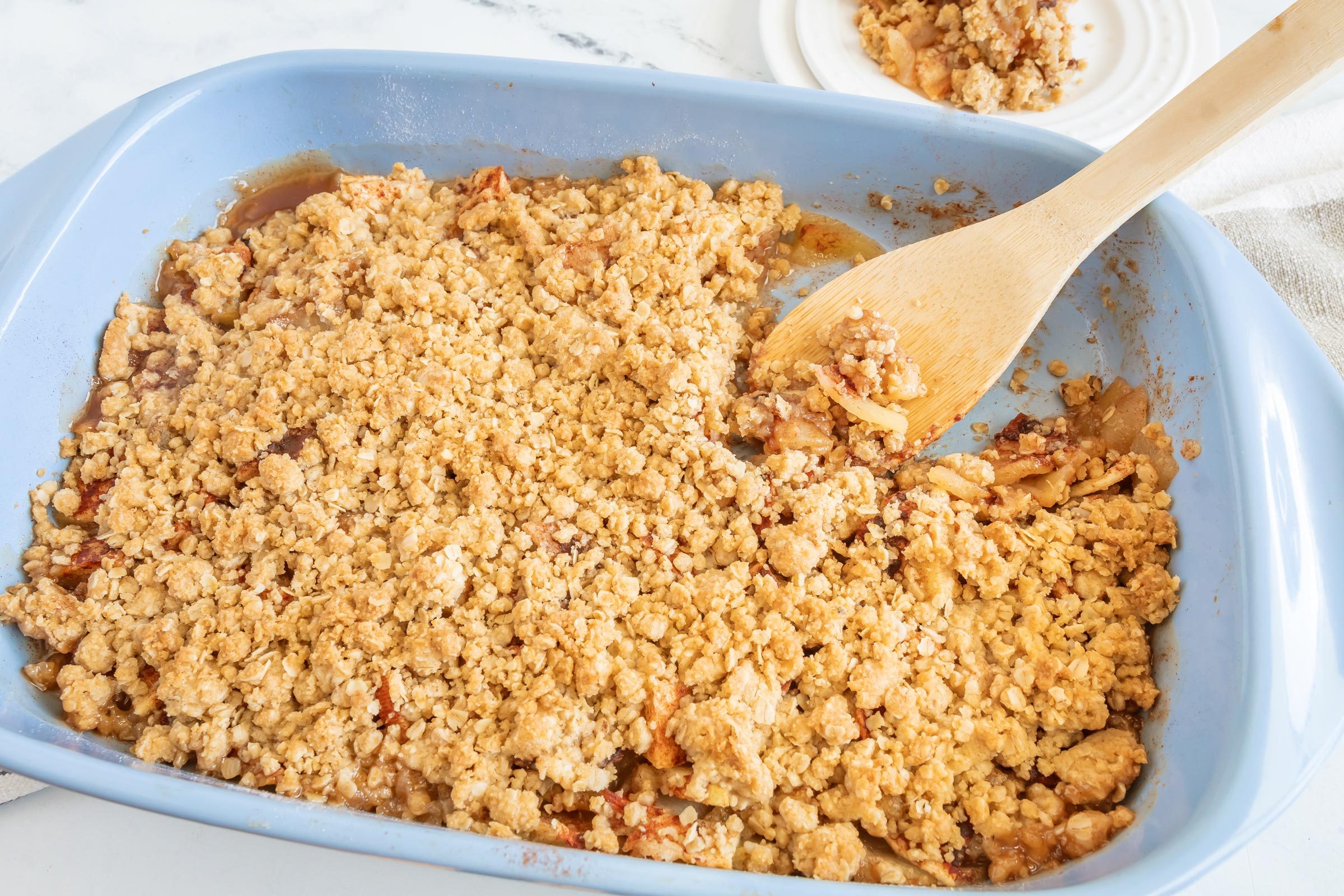 a blue baking dish with Amish 'apple Goodie and a wooden spoon