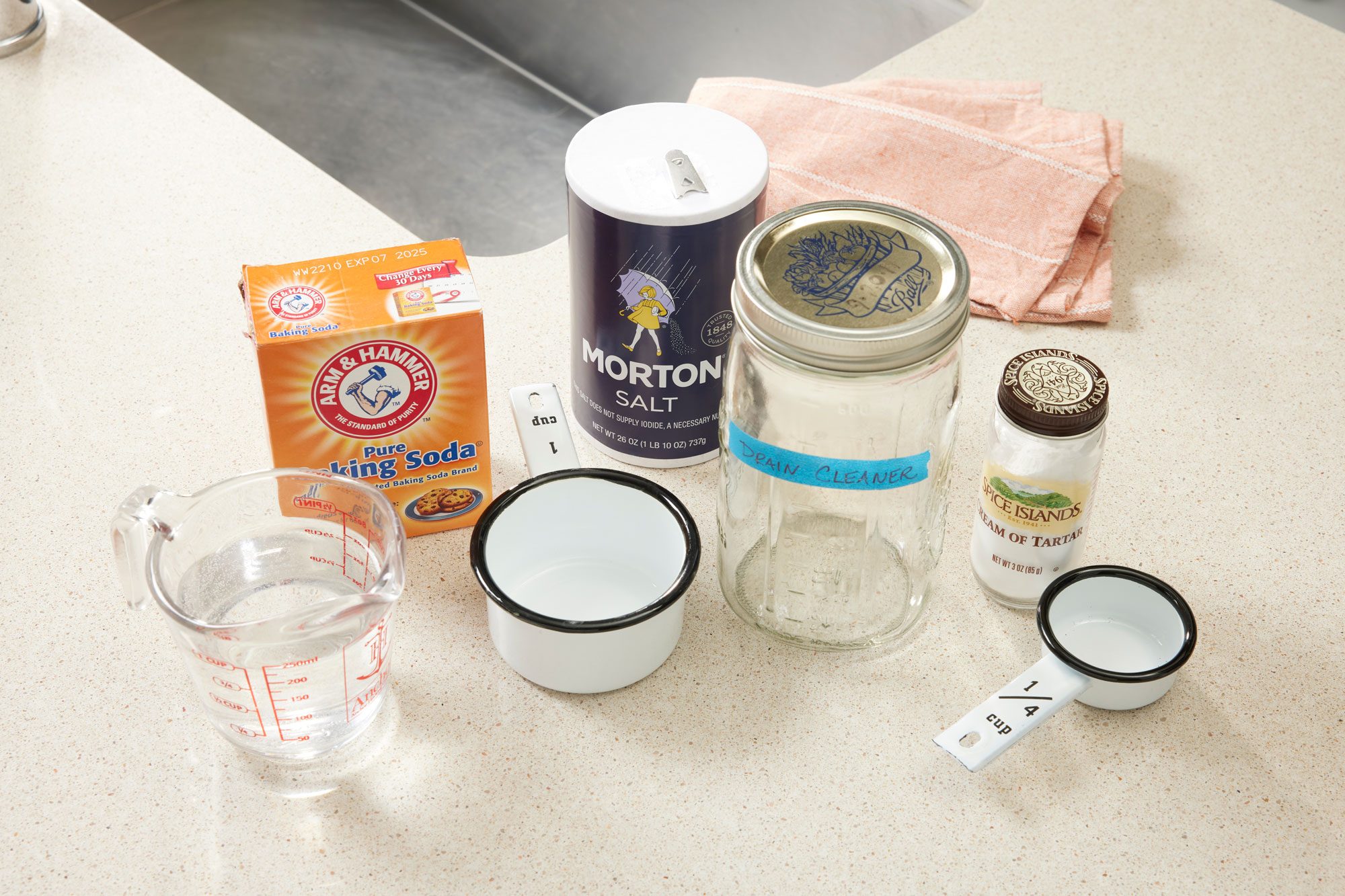 supplies for homemade drain cleaner arranged on the counter next to a kitchen sink