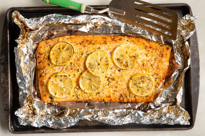 salmon in foil with lemon slices on a baking sheet