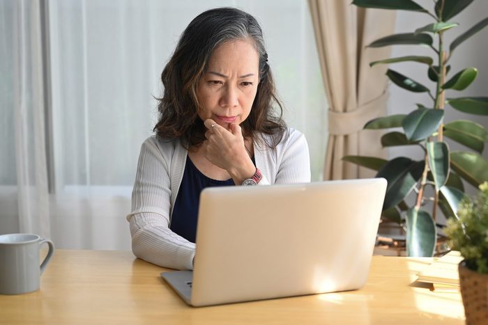 Serious mature woman checking business email during remote working from home.