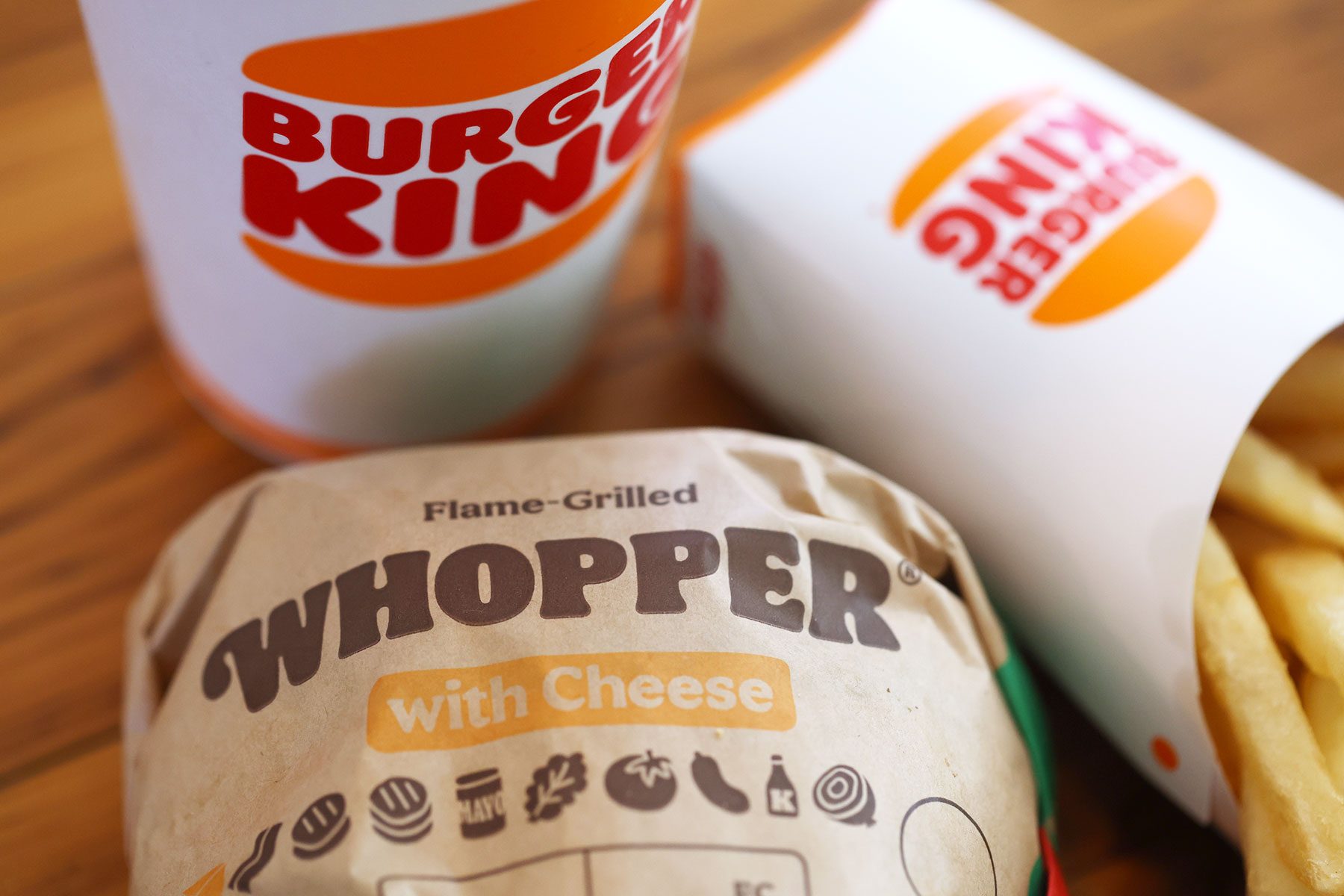 Burger King Whopper, French Fries and a Drink sit on a wooden table