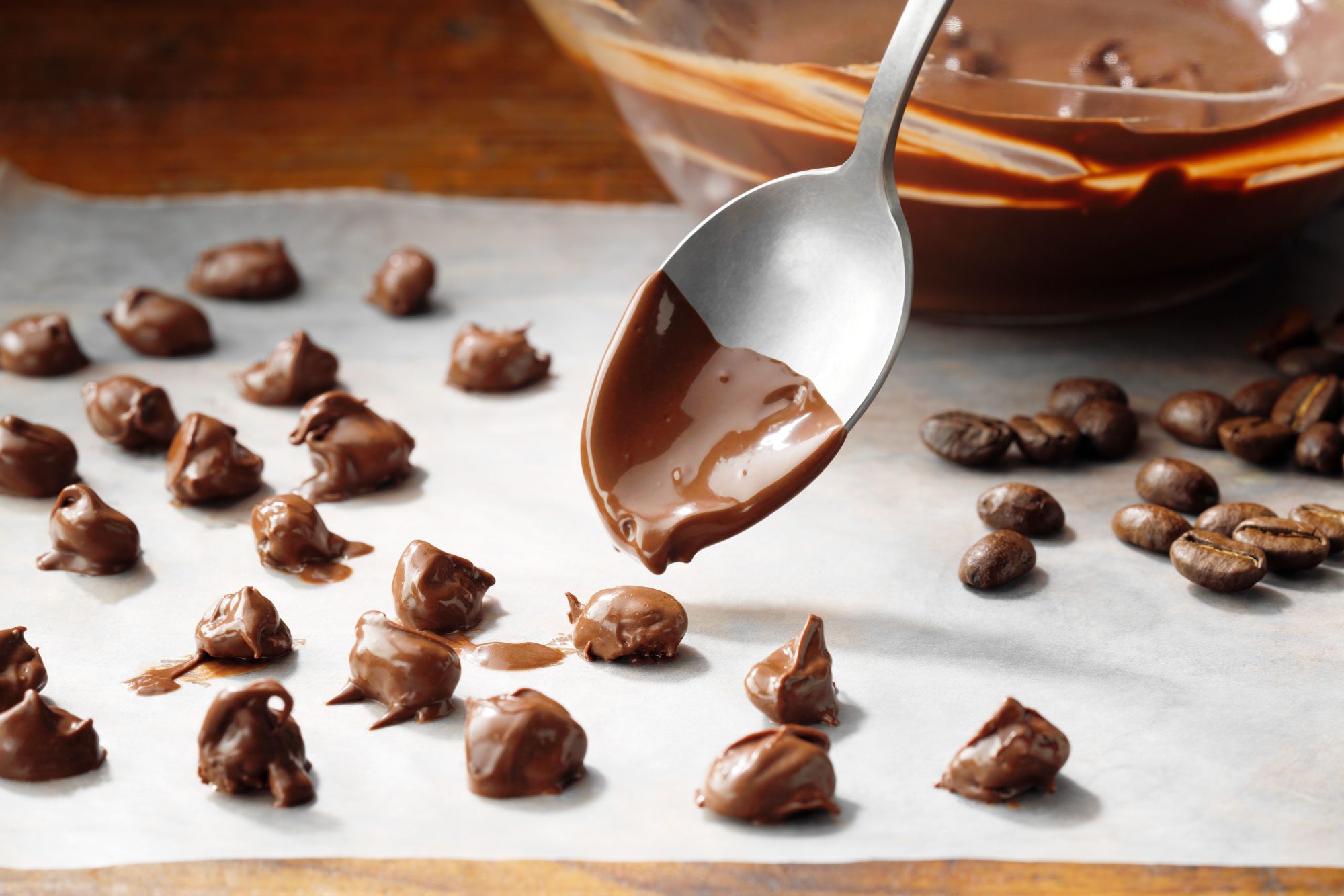 Espresso Beans Covered In Melted Chocolate Being Placed On Waxed Paper