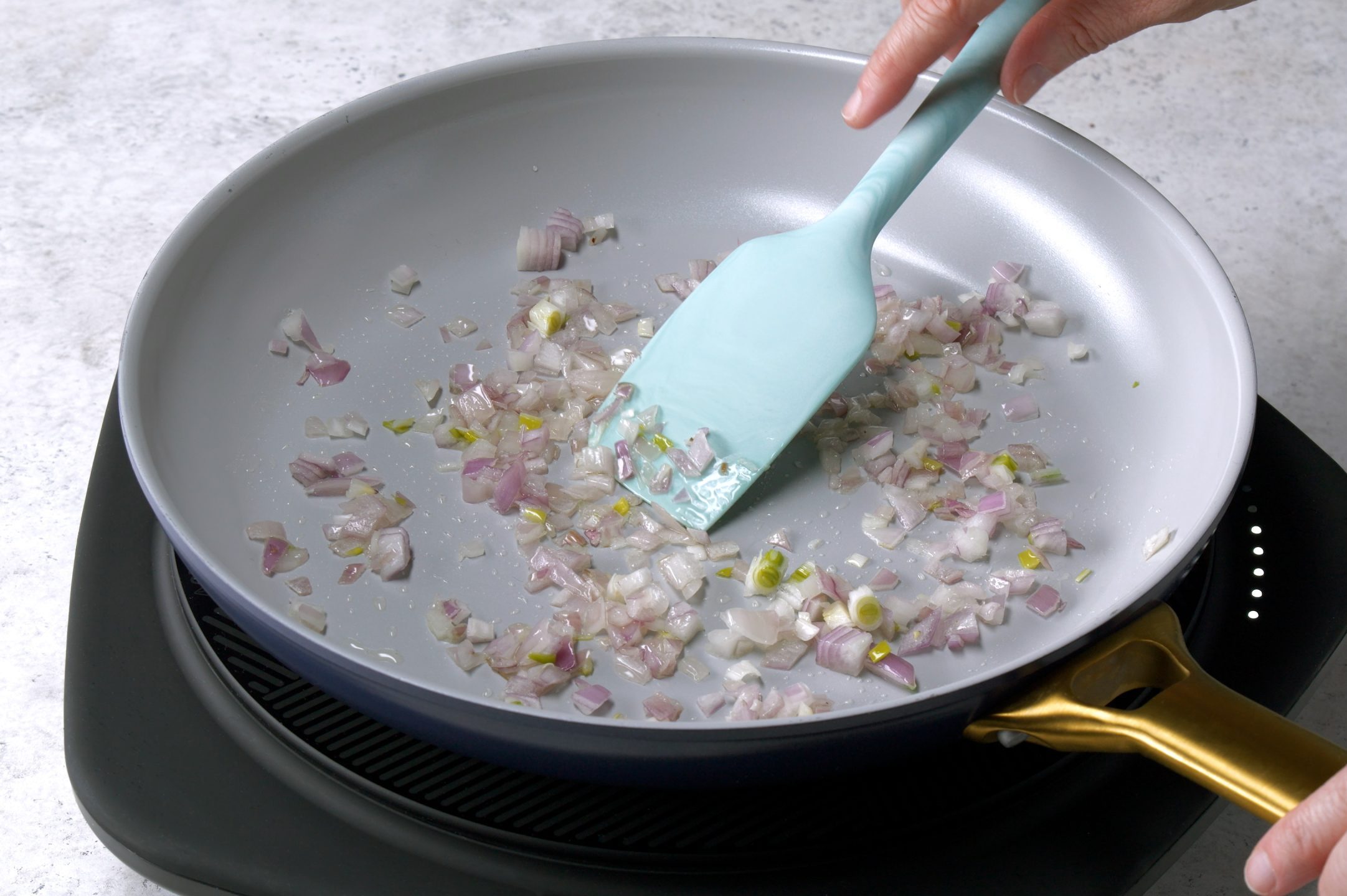 shallot in frying pan with hand