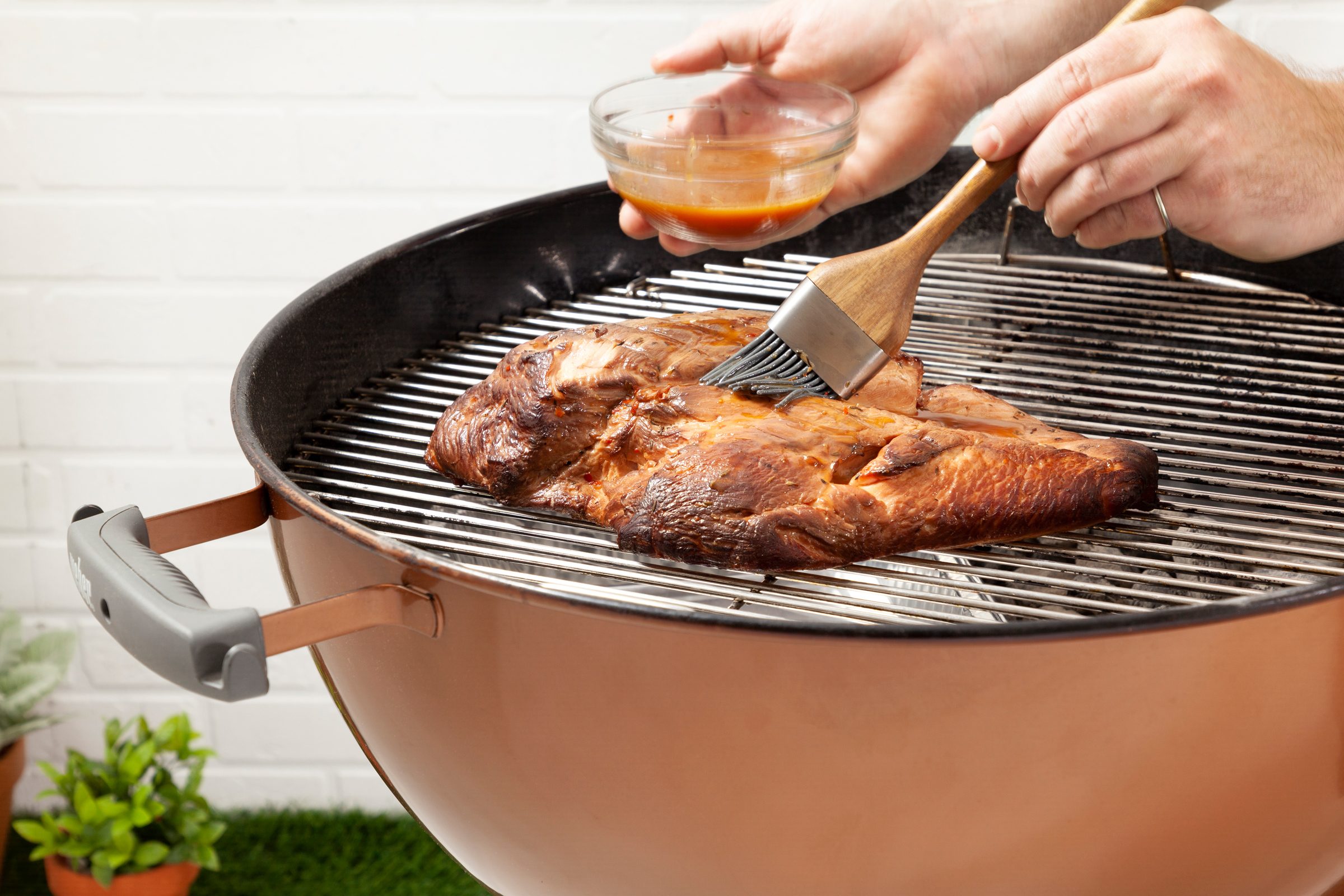 turkey on a grill being brushed with marinade