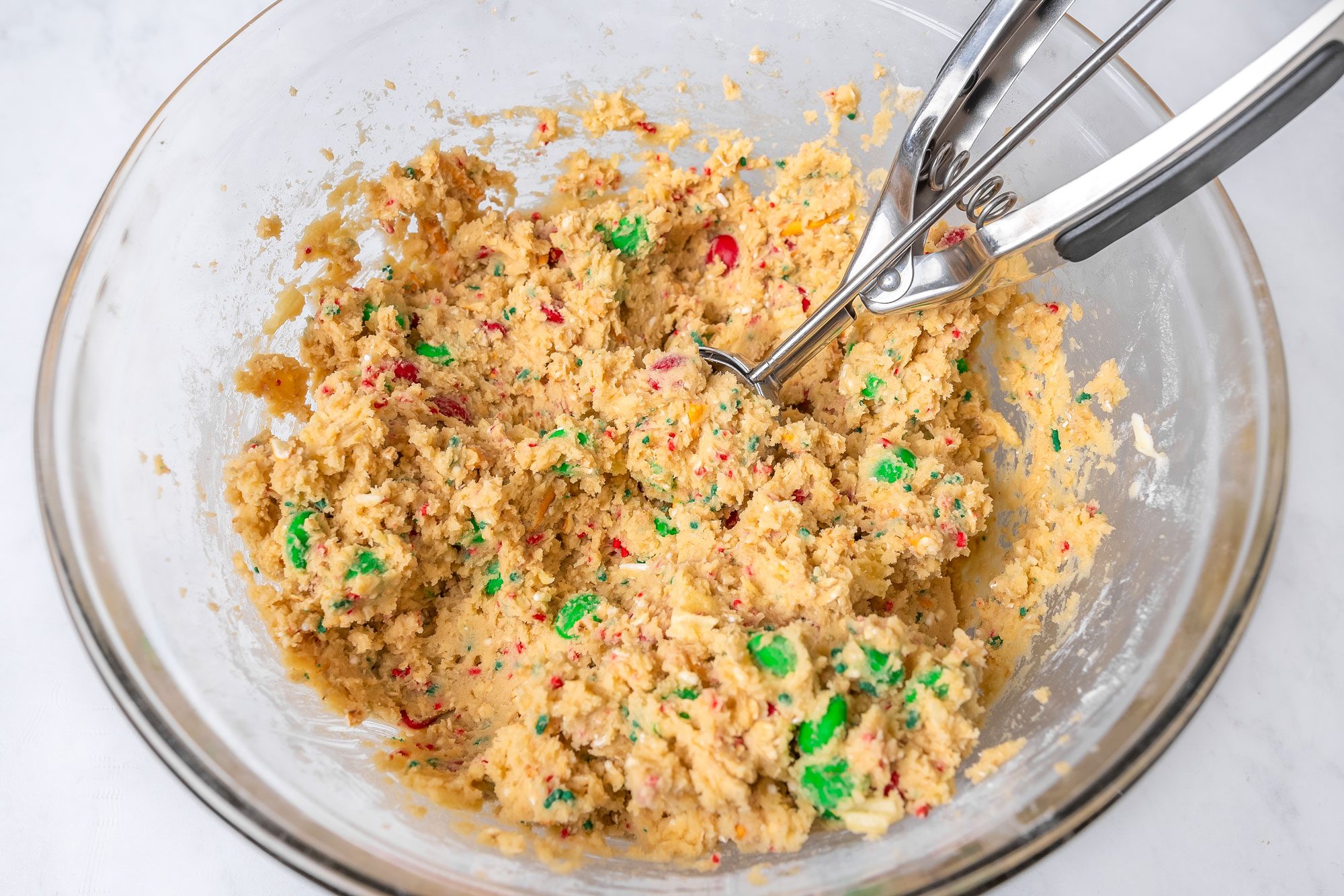 Kitchen Sink Christmas Cookies Dough in a Large Glass Bowl with a Cookie Scoop