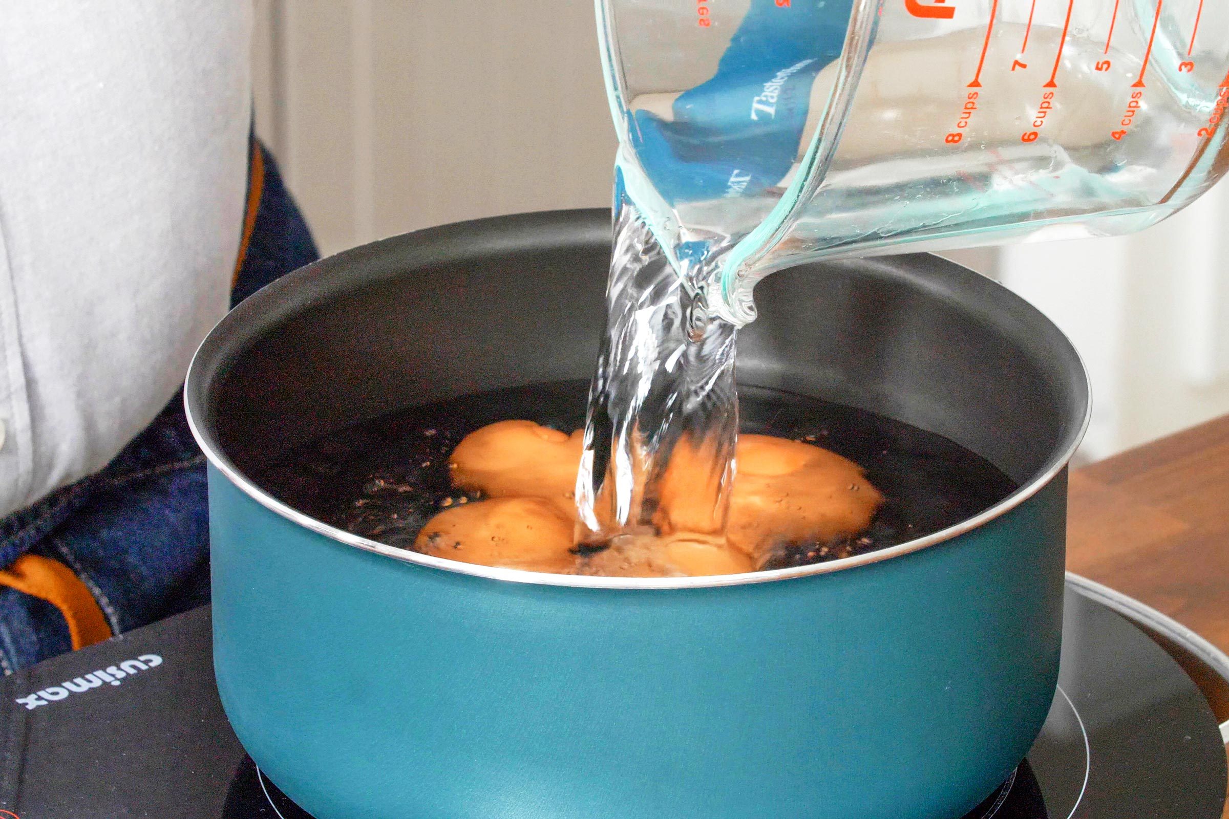 adding water and eggs to a large pot on the stove