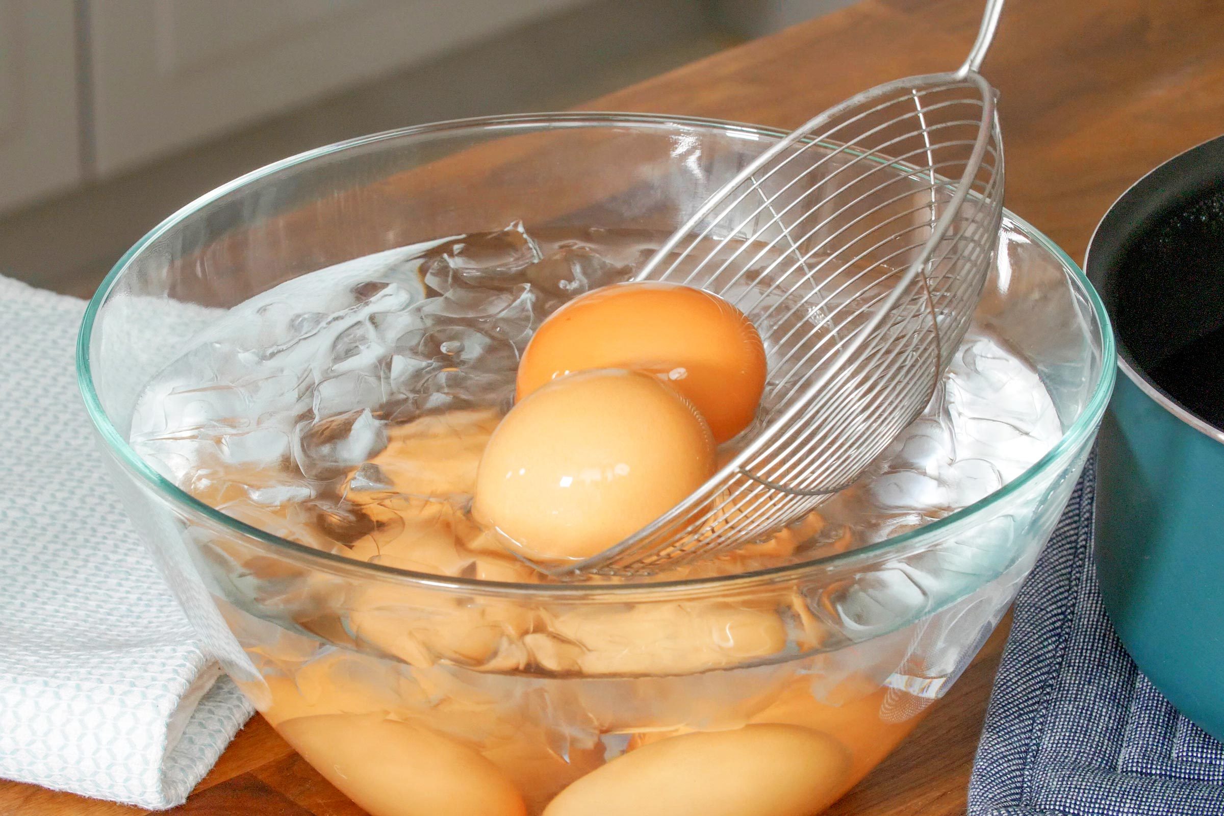 adding hard boiled eggs to a bowl of cold ice water