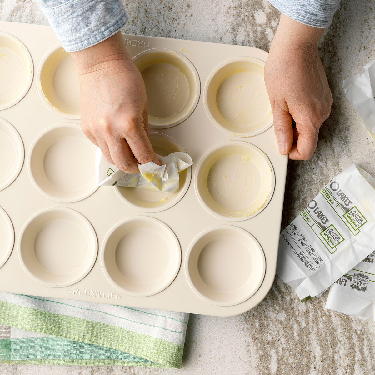 Rubbing butter on cupcake tray with butter paper