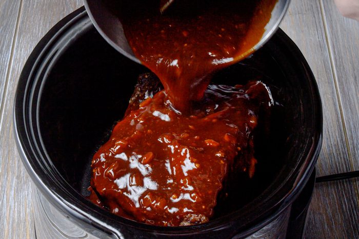 Return the brisket to the cooker and add barbecue sauce