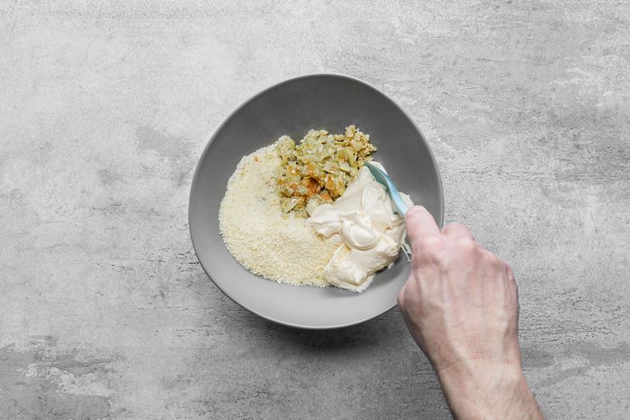 Mixing artichokes, mayonnaise, Parmesan in a small bowl