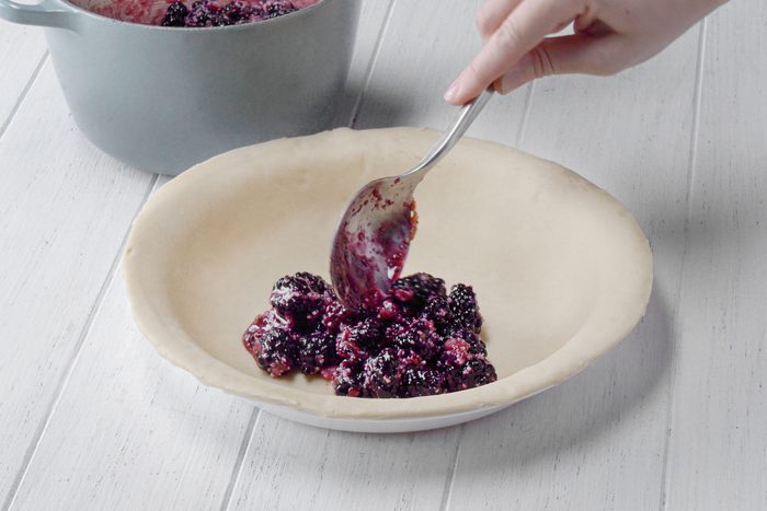 Filling the pie crust with Blackberry mixture with a spoon