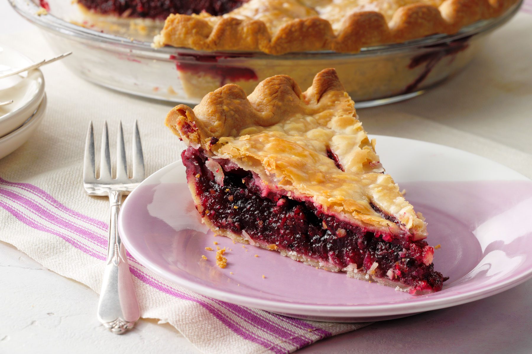 A slice of Blackberry Pie served in a plate on a table