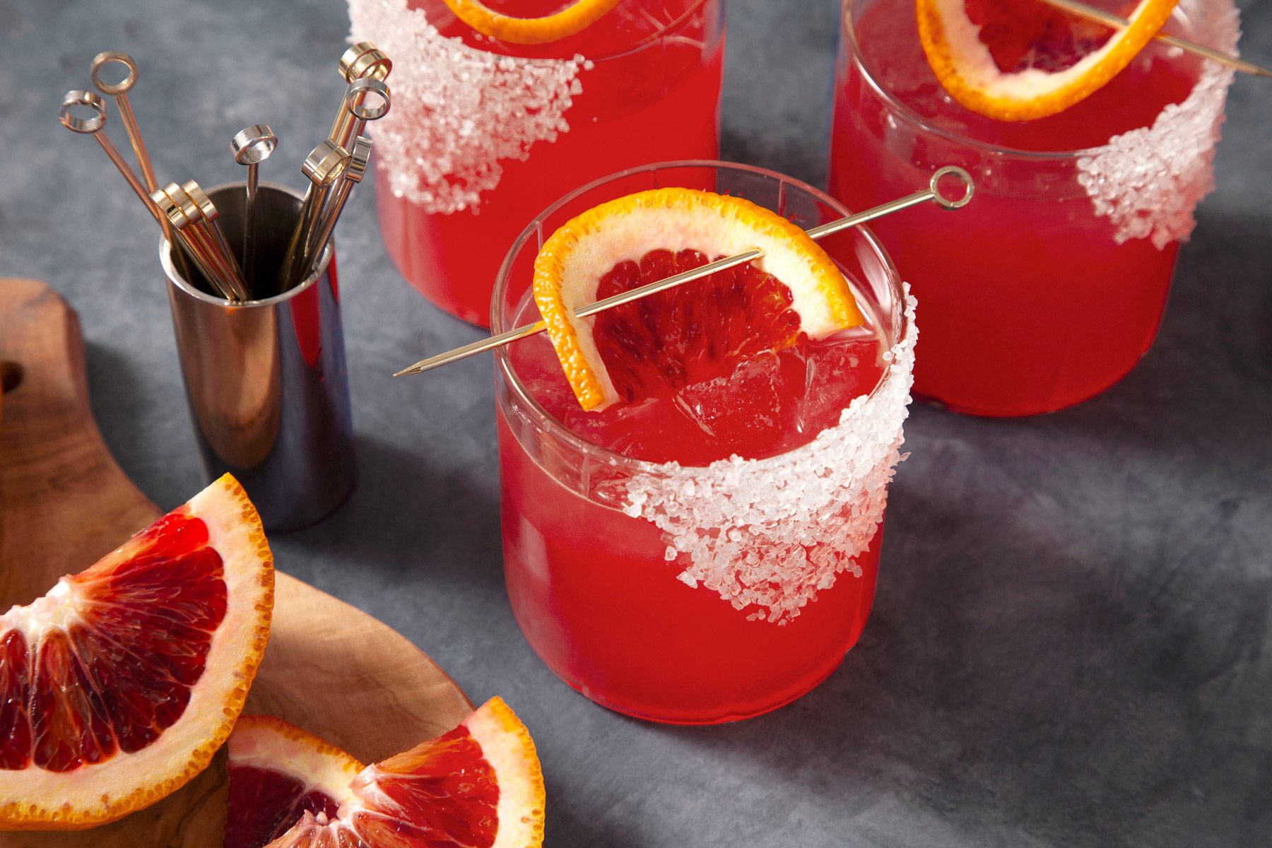A group of glasses of blood orange margarita with orange slices.