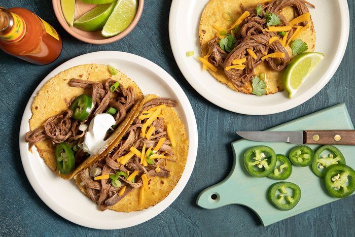 Brisket Tacos topped with lemon, jalapeños and cheese and served on plate