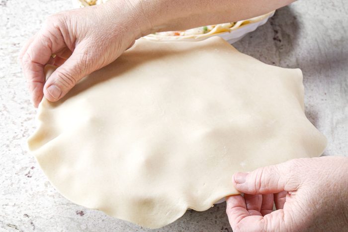 Adding the top crust on the pie plate