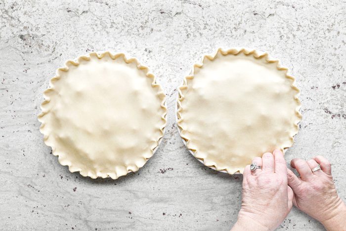 Sealing and trimming the edges of the pie crust.