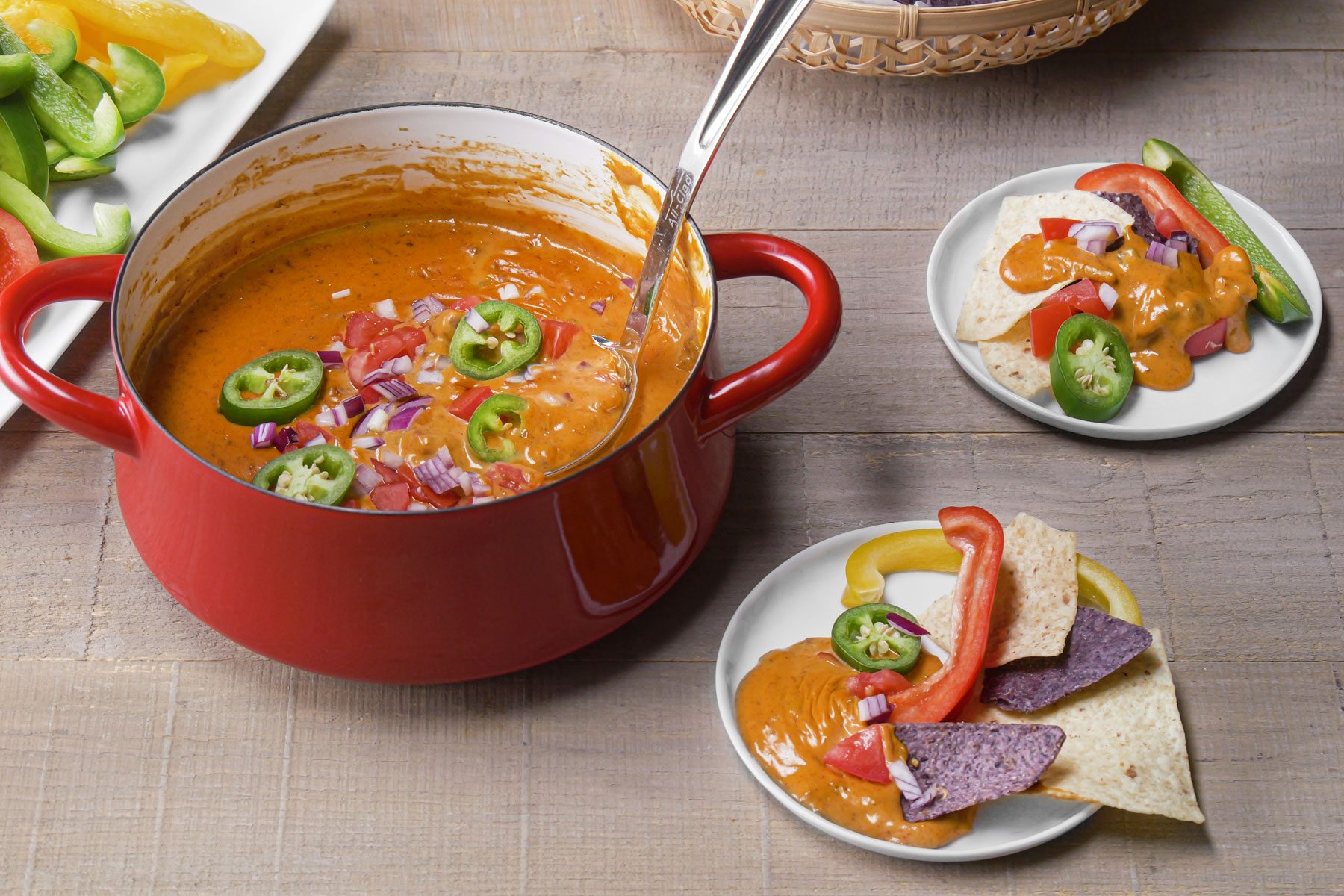 Chili Cheese Dip served in a plate with tortilla chips, pretzels and peppers on the side