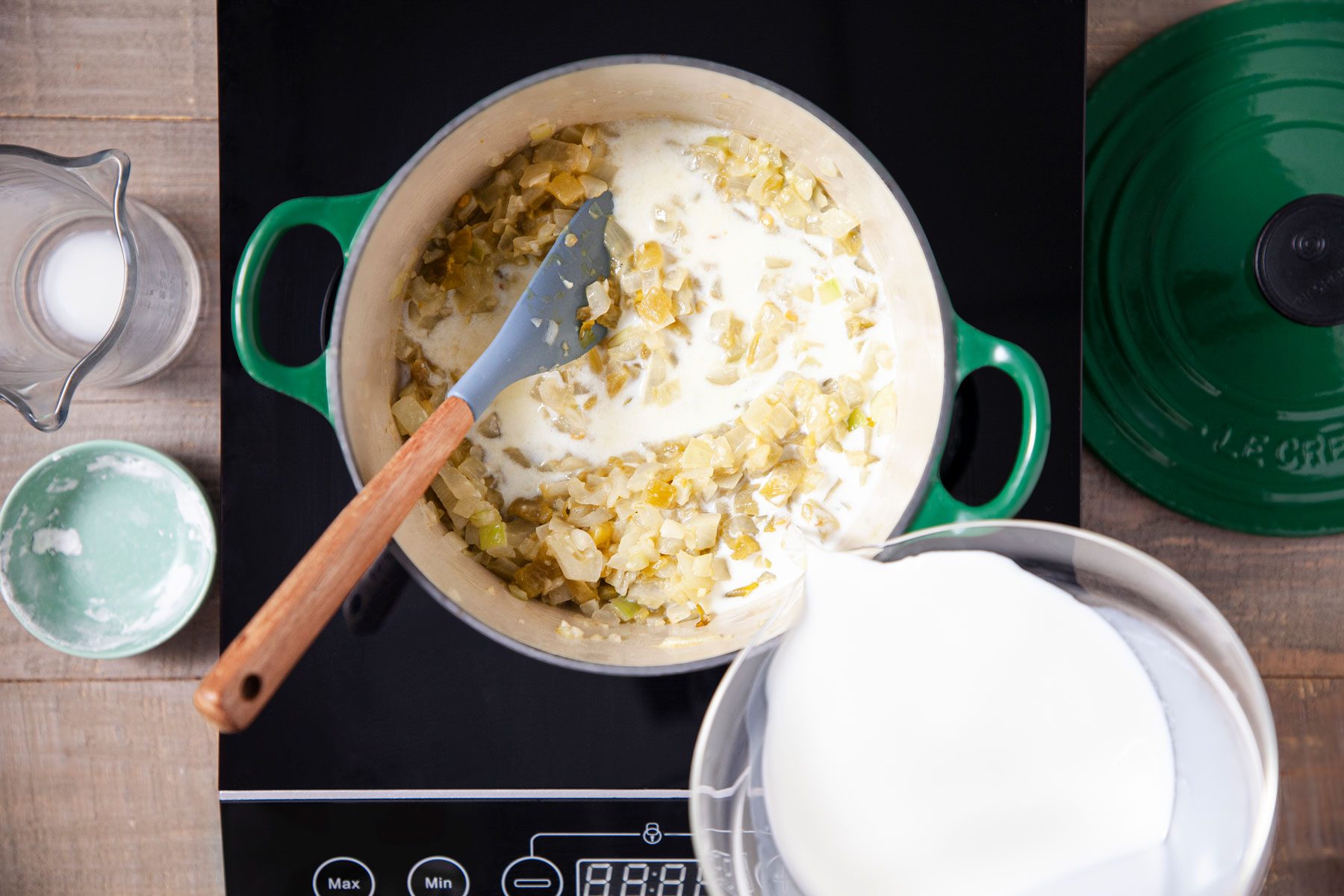 Pouring milk in onions and garlic in a saucepan