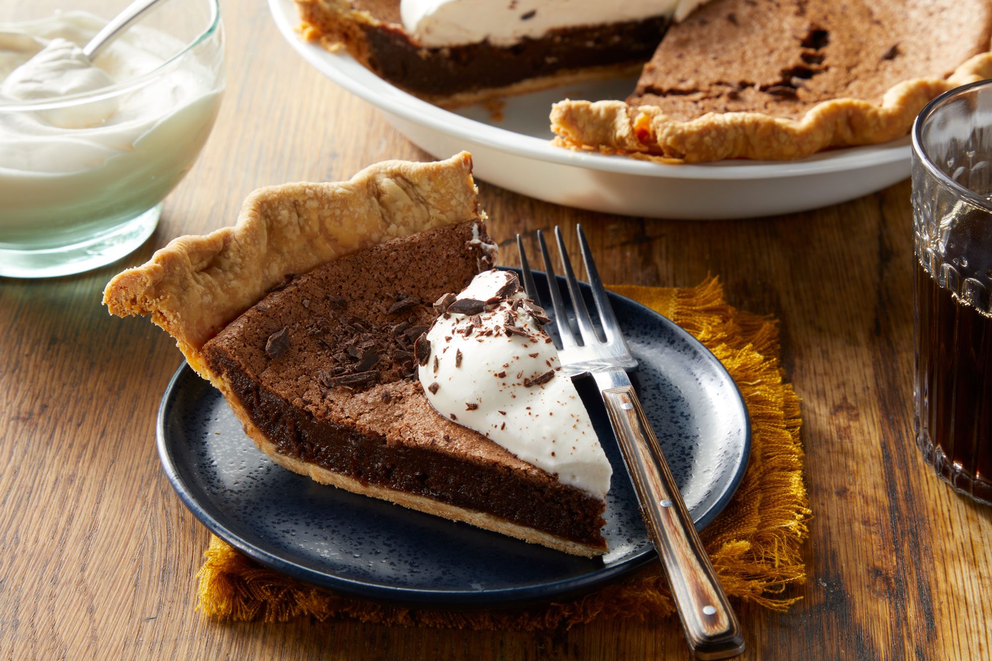 A slice of Chocolate Chess Pie with whipped cream served in a plate