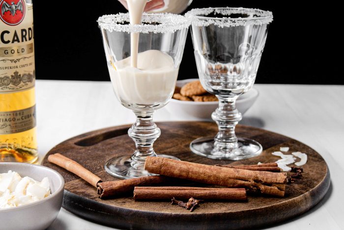 Coquito drink is poured in a glass in a wooden tray