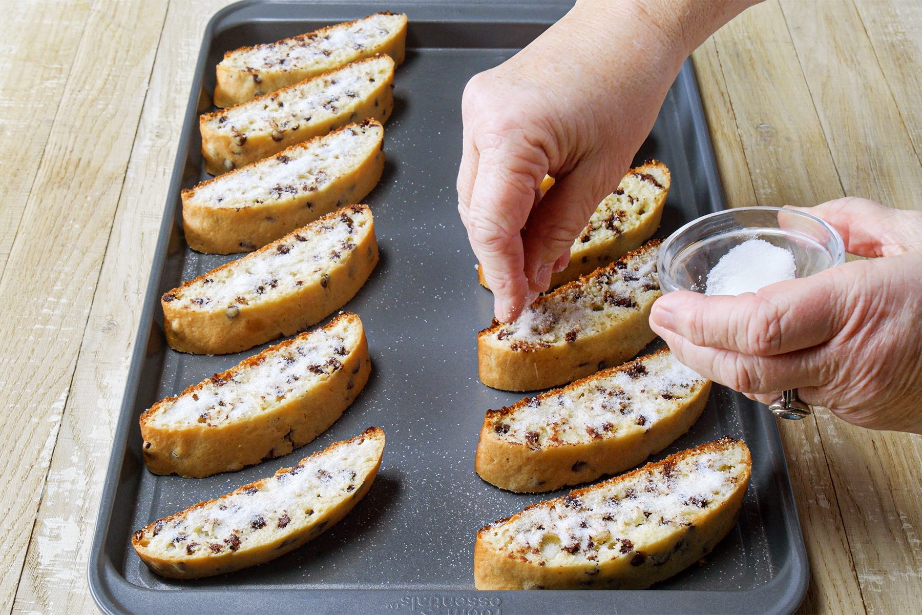 A person sprinkling sugar on bread